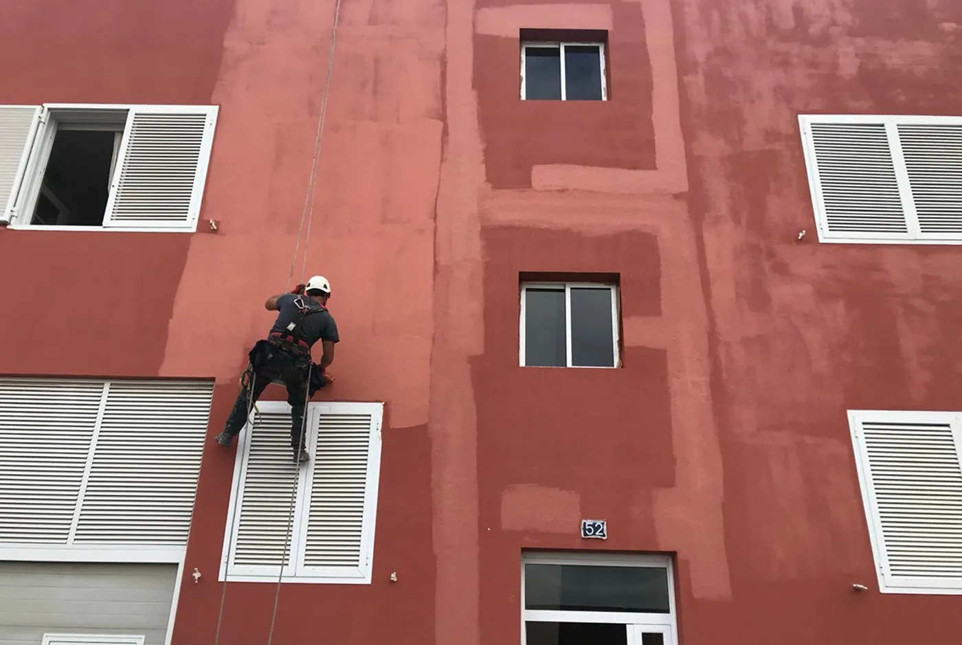 Operario trabajando en altura en la fachada de un edificio