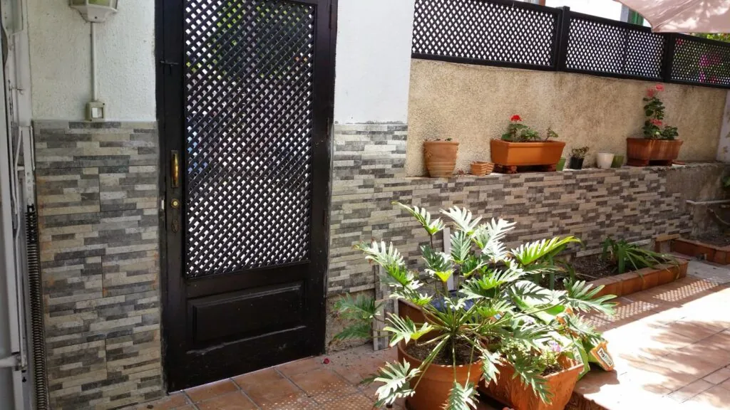Patio con muro revestido en piedra y puerta de forja